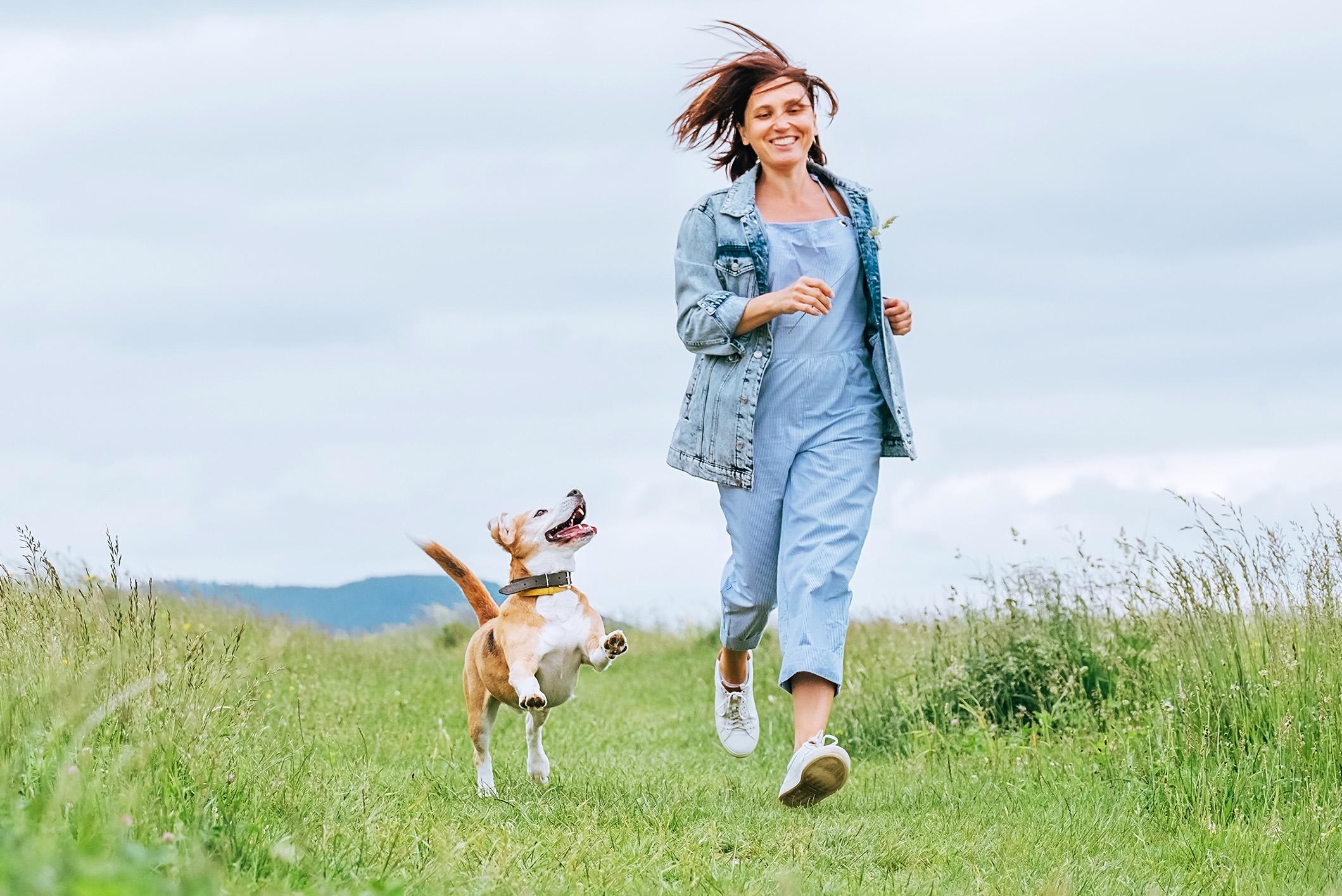 Woman with and her happy beagle dog running 