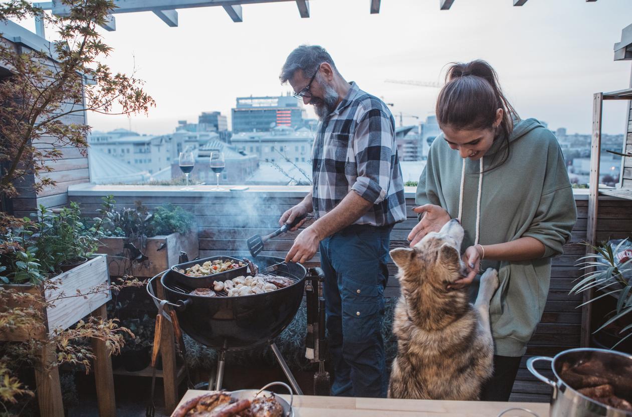 couple grills on patio with dog nearby