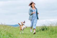 Woman with and her happy beagle dog running 