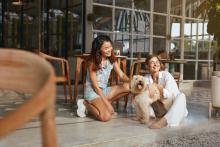two women sit on patio with dog
