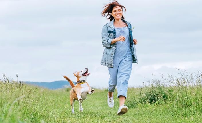 Woman with and her happy beagle dog running 