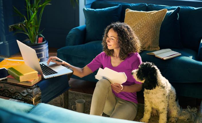 Woman sitting at laptop with white dog