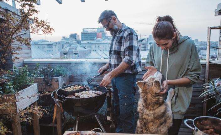 couple grills on patio with dog nearby