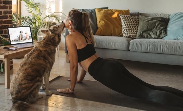 Woman doing yoga with dog beside her